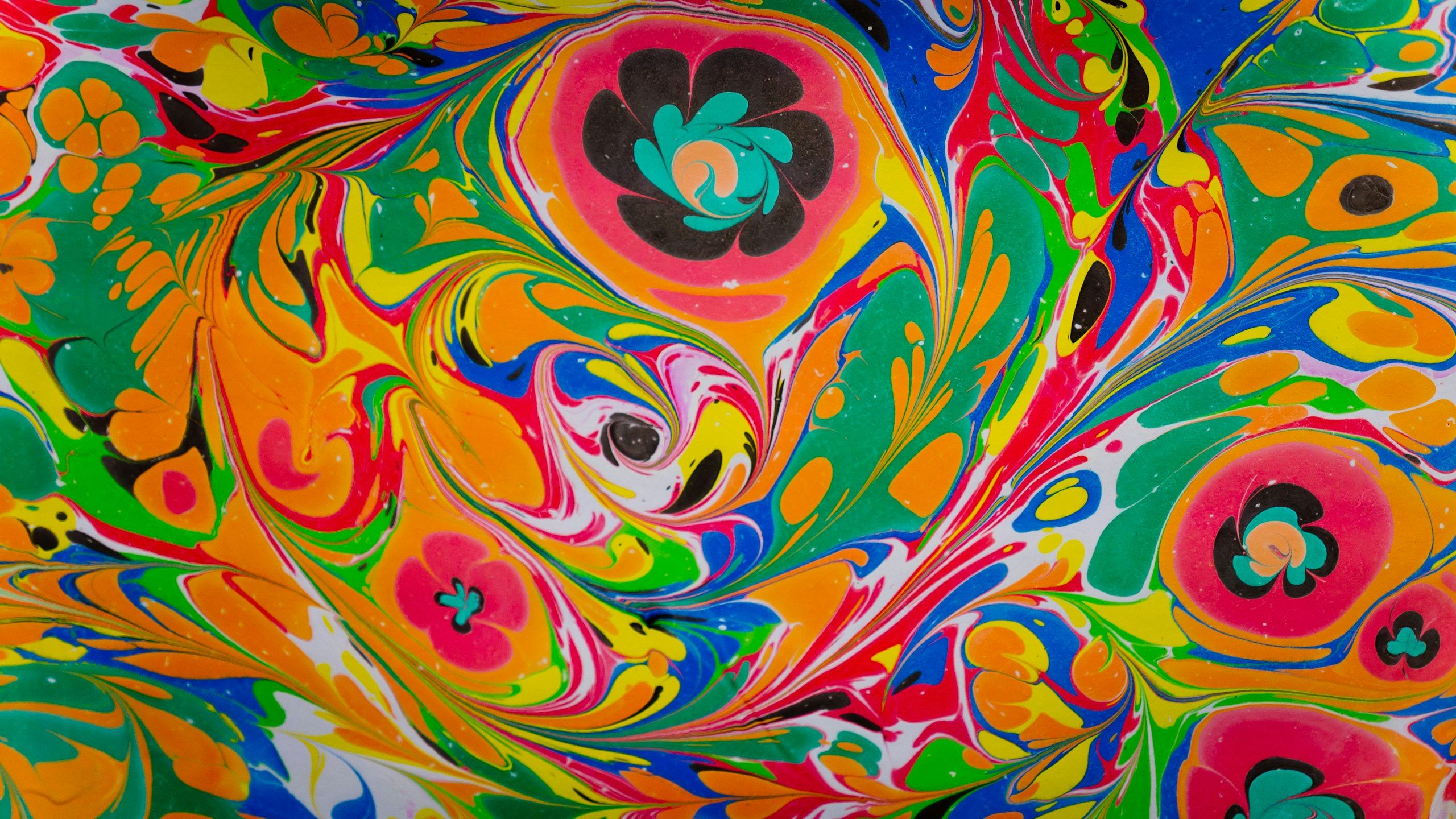 Swirling marbled paint in orange, pink, green, and blue